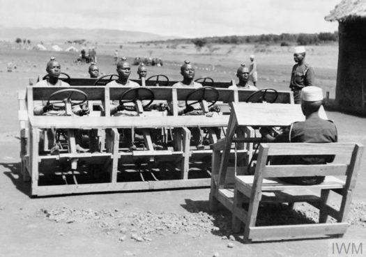 EAST AFRICANS BECOME MOTOR TRANSPORT DRIVERS, C. 13 DECEMBER 1943 (K 4943) Motor Transport Depot. Askaris learning to change gear. Note stones on head to stop learners looking down